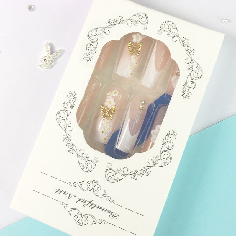 Pink and nude gradient nail art, golden butterflies and white flowers embellish delicate fingertips