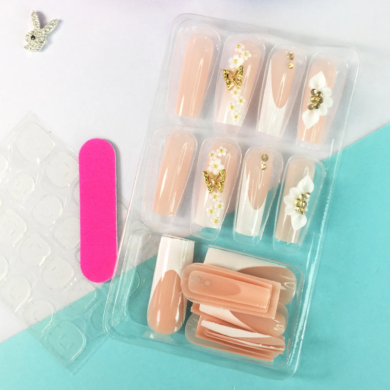 Pink and nude gradient nail art, golden butterflies and white flowers embellish delicate fingertips
