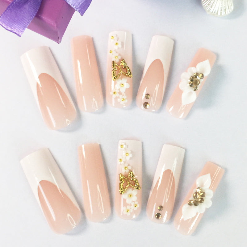 Pink and nude gradient nail art, golden butterflies and white flowers embellish delicate fingertips