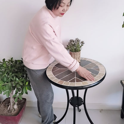 A small round stone table | with a colorful stone - inlaid tabletop and metal legs | an outdoor small round table to start a cozy leisure time.