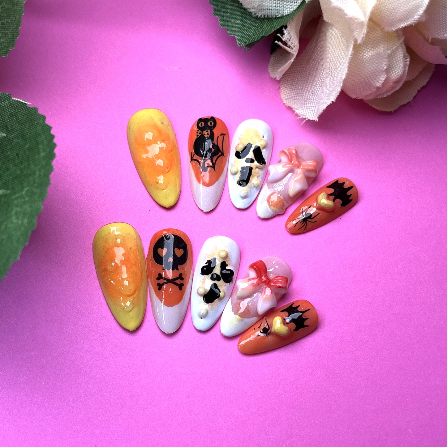 Halloween-themed nail art with skull, bat, and bow elements