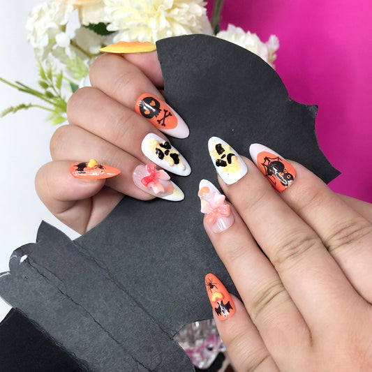 Halloween-themed nail art with skull, bat, and bow elements